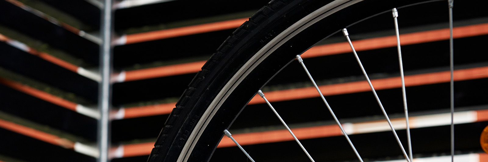 Abstract close up of a bike wheel with a background of a bike storage wall.